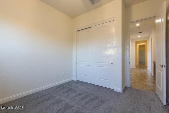 unfurnished bedroom featuring dark carpet and a closet