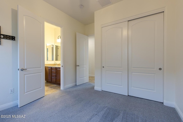 unfurnished bedroom featuring ensuite bathroom, a closet, light colored carpet, and sink