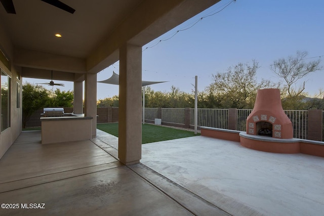 view of patio featuring area for grilling, ceiling fan, exterior kitchen, and an outdoor fireplace