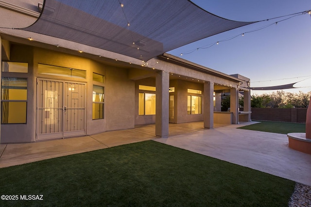 back house at dusk with a yard and a patio