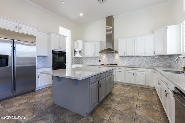 kitchen with wall chimney exhaust hood, a kitchen island, backsplash, built in appliances, and white cabinets