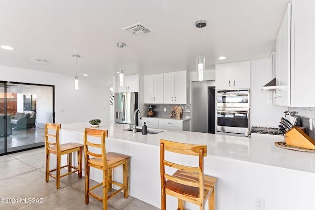 kitchen featuring sink, kitchen peninsula, a breakfast bar area, white cabinetry, and stainless steel appliances