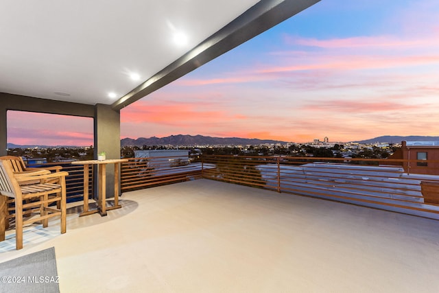 patio terrace at dusk featuring a mountain view and a balcony