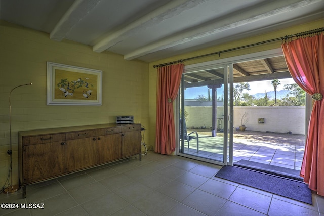 doorway featuring beam ceiling and light tile patterned floors