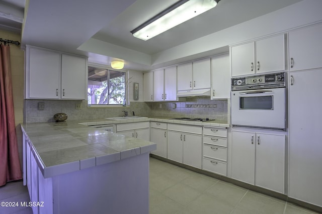 kitchen featuring white cabinets, sink, white appliances, and kitchen peninsula