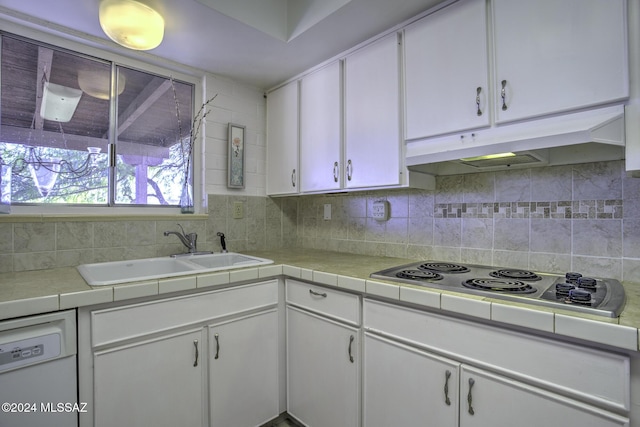 kitchen with dishwasher, backsplash, stainless steel electric stovetop, sink, and white cabinetry