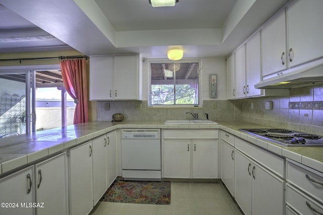 kitchen with white cabinetry, sink, white dishwasher, and a healthy amount of sunlight