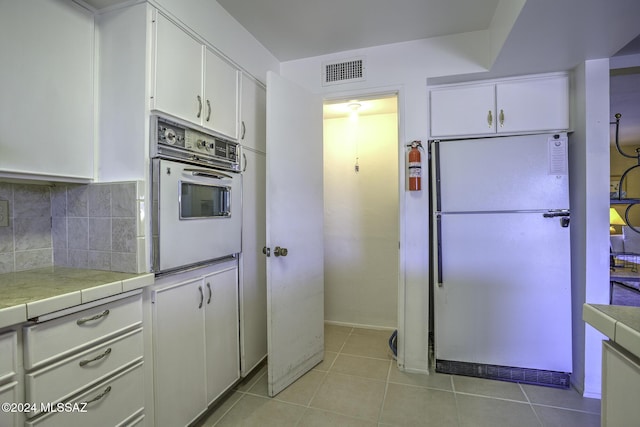 kitchen featuring white cabinets, backsplash, white fridge, and oven