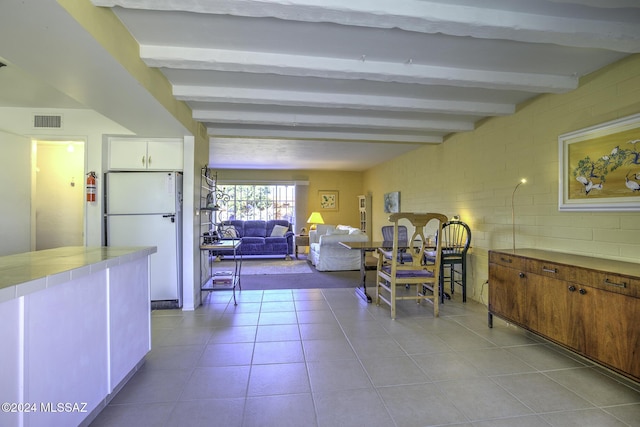 tiled dining room featuring beam ceiling