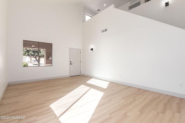 spare room featuring light hardwood / wood-style flooring and a towering ceiling