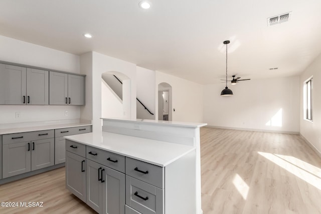 kitchen with gray cabinets, light hardwood / wood-style flooring, ceiling fan, and a kitchen island