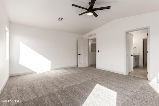 unfurnished bedroom featuring light carpet, ensuite bathroom, ceiling fan, and lofted ceiling