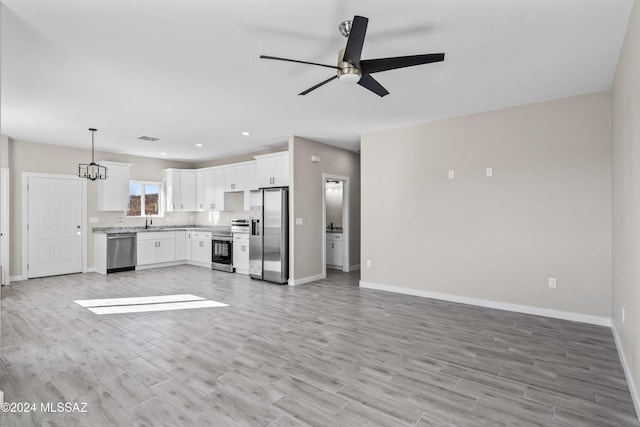 kitchen featuring ceiling fan with notable chandelier, decorative light fixtures, light hardwood / wood-style floors, white cabinetry, and stainless steel appliances