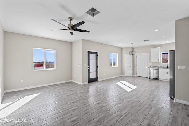 unfurnished living room featuring plenty of natural light, ceiling fan, and light wood-type flooring