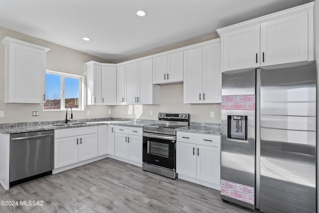 kitchen featuring white cabinets, stainless steel appliances, light stone countertops, and sink