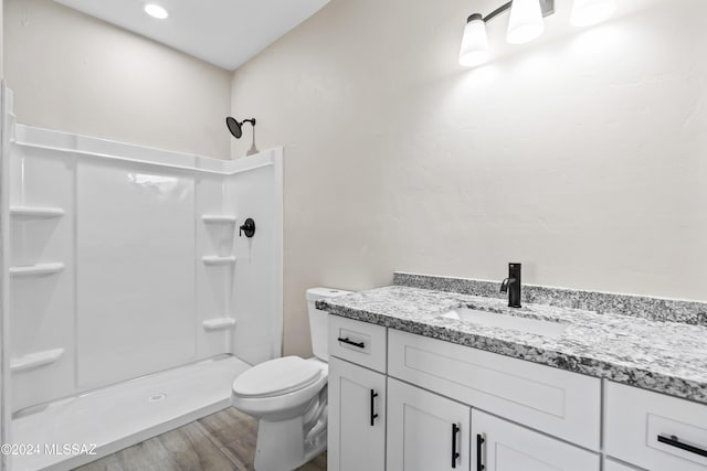 bathroom with wood-type flooring, vanity, toilet, and walk in shower