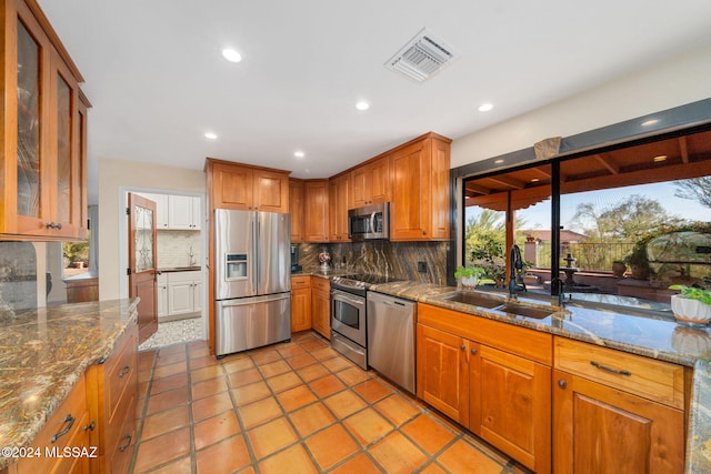 kitchen with stainless steel appliances, light stone counters, tasteful backsplash, and sink