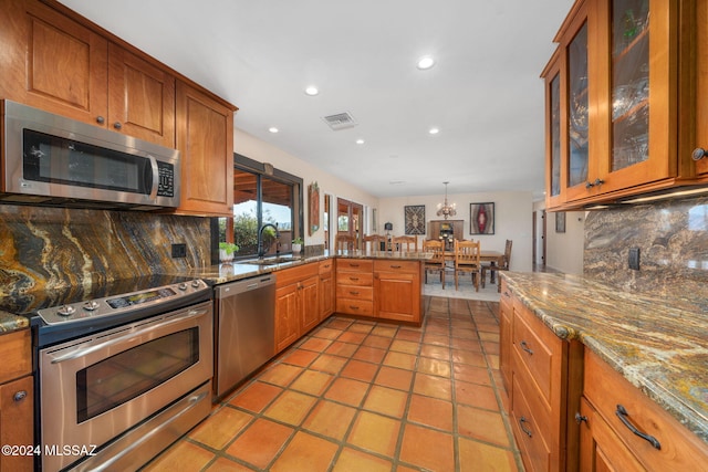 kitchen with decorative light fixtures, stainless steel appliances, tasteful backsplash, and sink