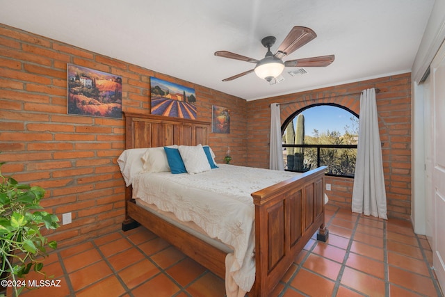 bedroom featuring tile patterned flooring, a closet, ceiling fan, and brick wall