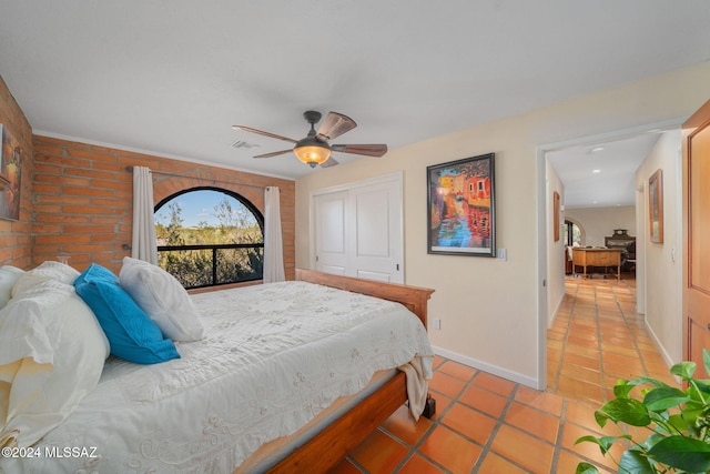 tiled bedroom with ceiling fan and a closet