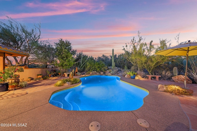 pool at dusk featuring a patio area