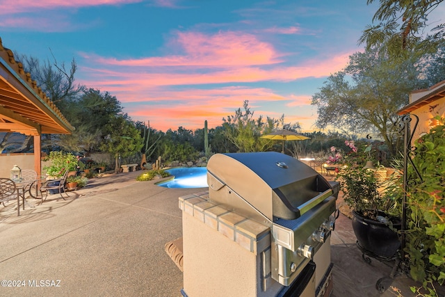 patio terrace at dusk featuring a grill