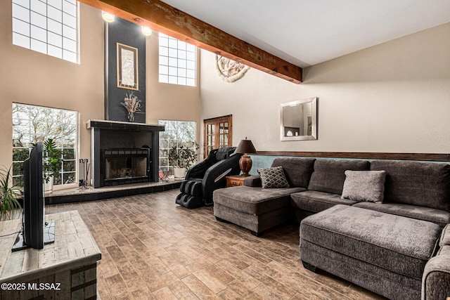 living room featuring a towering ceiling, wood-type flooring, and beam ceiling