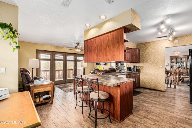 kitchen featuring a kitchen bar, sink, stainless steel counters, and a textured ceiling