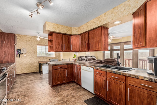 kitchen featuring sink, dishwasher, ceiling fan, a textured ceiling, and kitchen peninsula