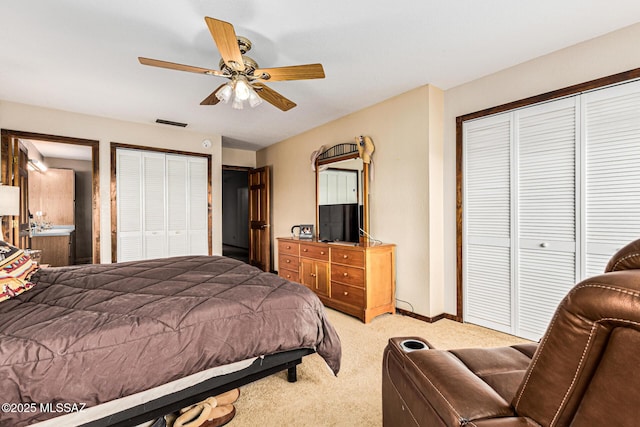 carpeted bedroom with ceiling fan and two closets