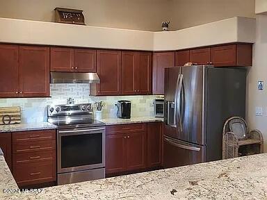 kitchen with backsplash, light stone counters, and stainless steel appliances