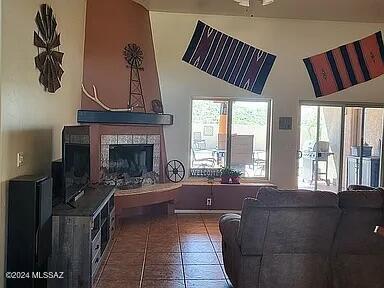 tiled living room with ceiling fan and a tiled fireplace