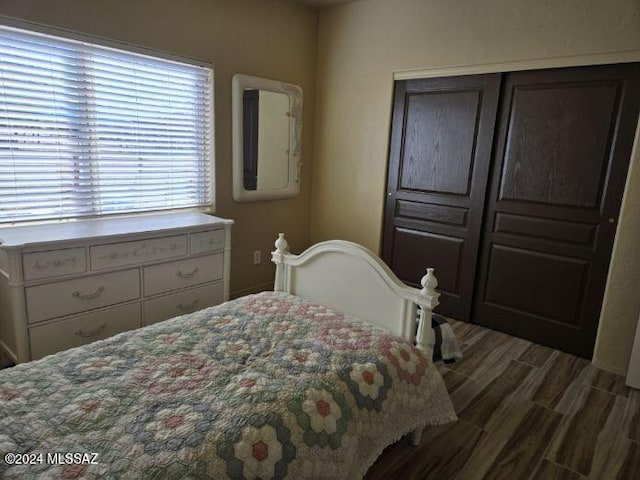 bedroom with dark wood-type flooring and a closet