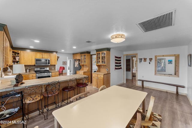 kitchen featuring kitchen peninsula, appliances with stainless steel finishes, tasteful backsplash, sink, and hardwood / wood-style flooring