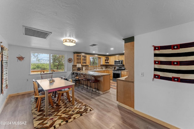 dining space featuring light hardwood / wood-style flooring and a textured ceiling