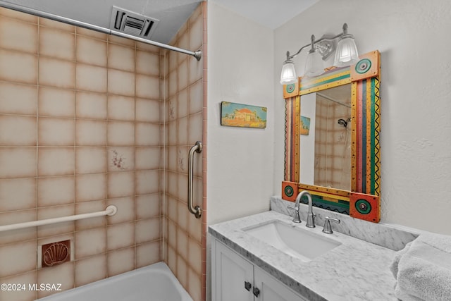 bathroom featuring vanity and tiled shower / bath