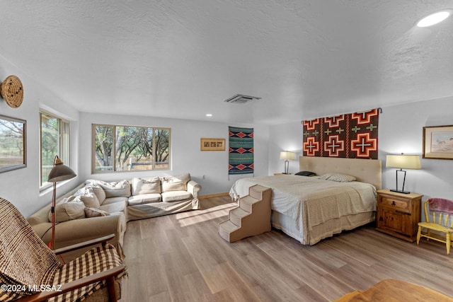 bedroom with a textured ceiling and light hardwood / wood-style flooring