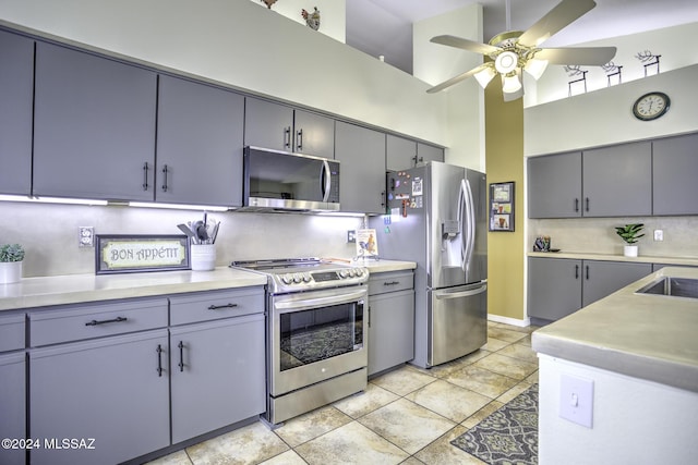 kitchen with appliances with stainless steel finishes, backsplash, ceiling fan, light tile patterned floors, and a high ceiling