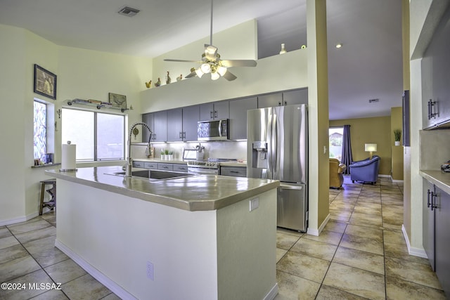 kitchen with a kitchen island with sink, high vaulted ceiling, sink, ceiling fan, and stainless steel appliances