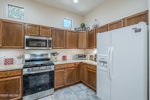 kitchen featuring light tile patterned floors, decorative backsplash, and stainless steel appliances