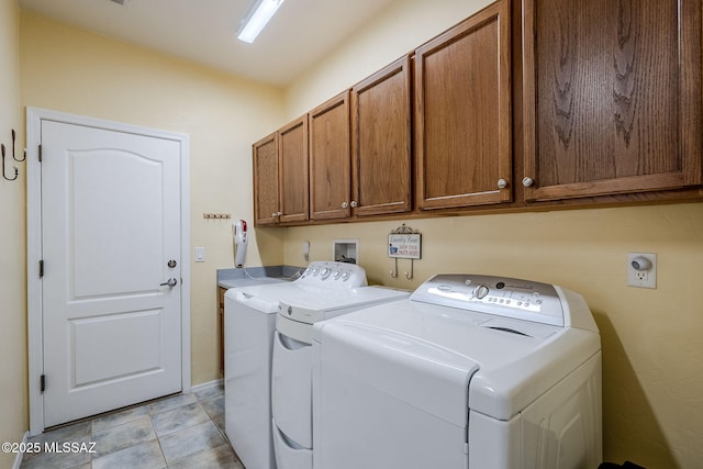 clothes washing area featuring cabinets, separate washer and dryer, and light tile patterned floors