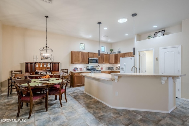 kitchen featuring stainless steel appliances, a kitchen breakfast bar, a kitchen island with sink, and hanging light fixtures