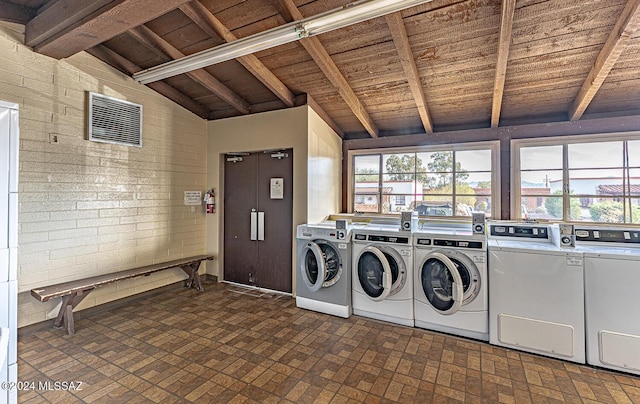 laundry area with washing machine and dryer, wooden ceiling, and brick wall