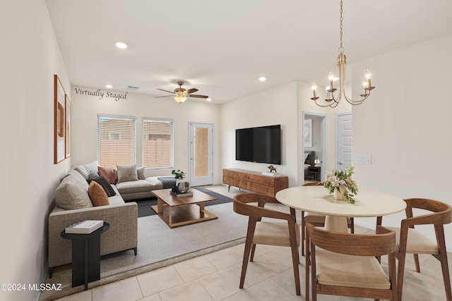 tiled living room with ceiling fan with notable chandelier