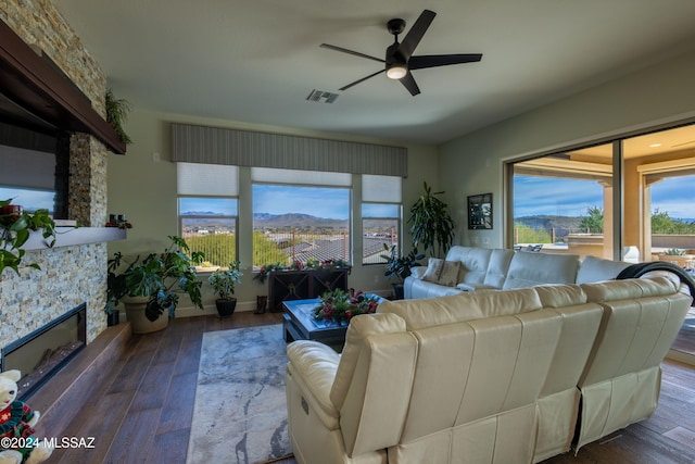 living room featuring a mountain view, a fireplace, ceiling fan, and dark wood-type flooring