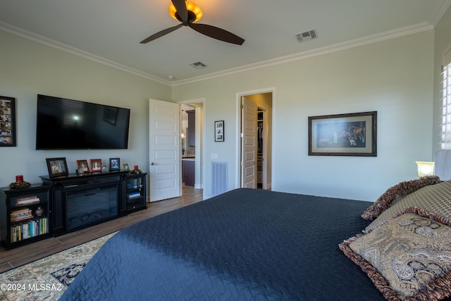 bedroom featuring ornamental molding, a spacious closet, ceiling fan, and dark wood-type flooring