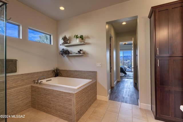 bathroom featuring a relaxing tiled tub, a wealth of natural light, and hardwood / wood-style flooring