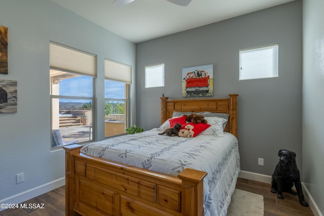 bedroom with ceiling fan, dark hardwood / wood-style flooring, and multiple windows