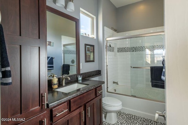 full bathroom featuring tile patterned flooring, toilet, combined bath / shower with glass door, and vanity