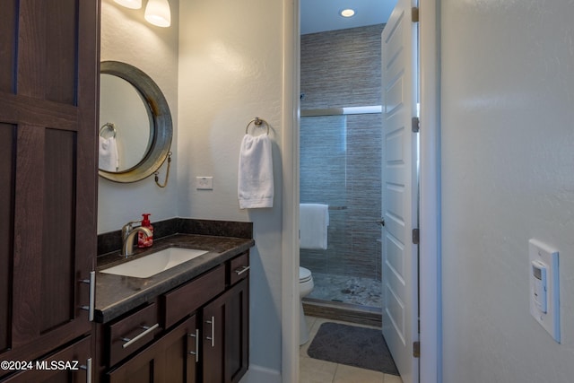 bathroom featuring tile patterned flooring, vanity, toilet, and a shower with door